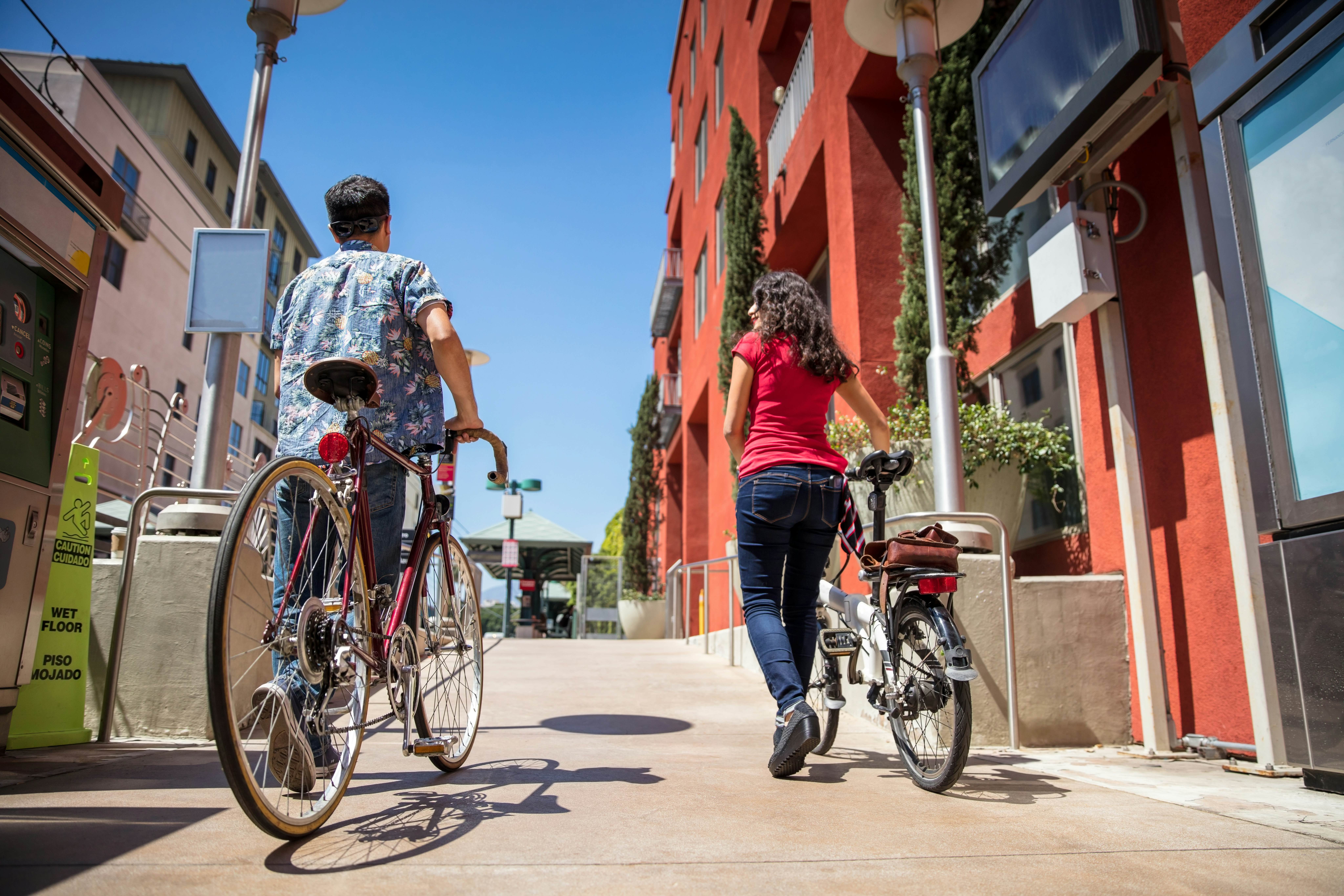 A man and woman with their bicycles near a light rail station in Pasadena, California.